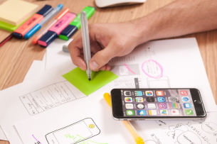 Pic of iPhone, papers an hand scribbling on postit note